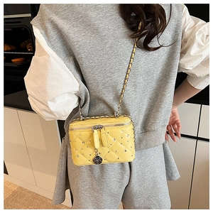 Detail of yellow quilted box bag featuring crystal studs and camellia zipper charm
