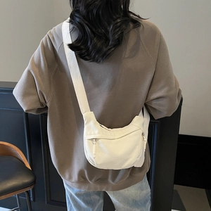 Rear view of white minimalist canvas crescent bag with adjustable wide strap on model