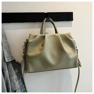 Detail view of pistachio green litchi grain leather bucket bag hanging on a rack