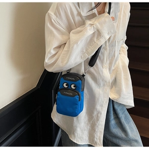 Detail of bright blue nylon phone bag with eye patterns and adjustable strap