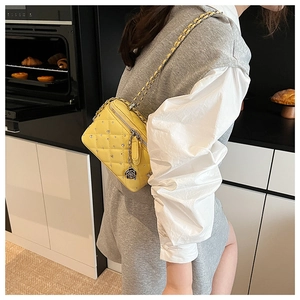 Detail of yellow quilted box bag with crystal studs and camellia floral pendant