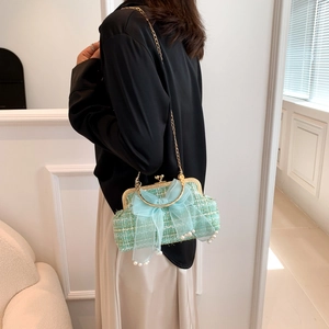 Close-up of mint green tweed shell bag featuring a blue tulle bow and pearl charms