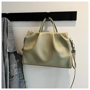 Detail of light green bucket bag showing lychee grain leather texture and handle on a hook
