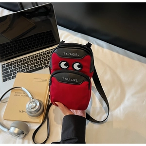 Detail of red and black canvas crossbody bag with cartoon eye design and dual zip pockets