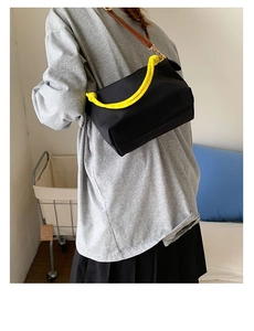 Detail of nylon crossbody bag featuring yellow rope handle and brown leather strap