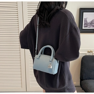 Detailed back view of a light blue pebble leather Boston bag styled with a grey hoodie