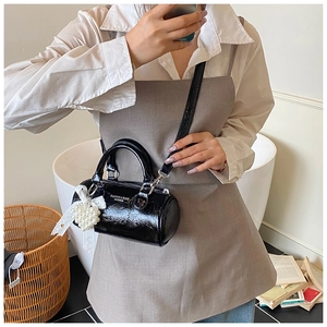 Retro black cylinder crossbody bag with heart pearl charm shown on model in a soft room