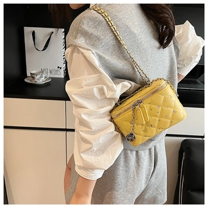 Close-up of yellow quilted crossbody bag with diamond accents and camellia charm