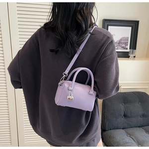 Close-up of lilac lychee grain leather mini bag with silver lock charm on a model