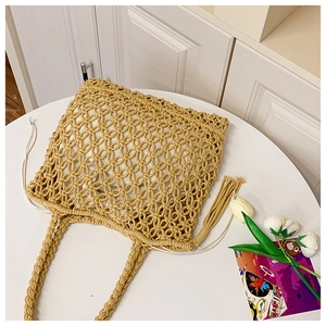 Detail of macrame straw tote bag showing intricate weave, tassels, and inner drawstring pouch
