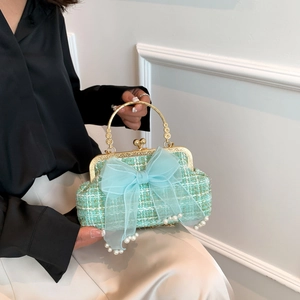 Close-up of woven mint tweed shell bag featuring a blue mesh bow with elegant pearl accents