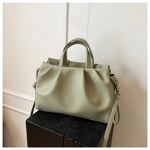 Detail of light green bucket bag showing lychee grain leather texture and pleated design