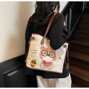 Detail of large white tote bag with cute bear print and brown shoulder strap on model