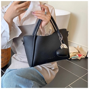 Detail of black pebbled leather tote with heart charm and sturdy dual handles