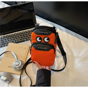 Close-up of vibrant orange crossbody bag with cartoon eyes and TYPAGIRL text detail