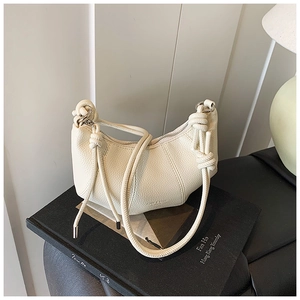 Detail der elfenbeinfarbenen Tasche aus genarbtem Leder mit modischem geknotetem Riemen