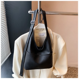 Detail der schwarzen Hobo-Tasche aus genarbtem Leder mit silberner Schnalle auf weißem Anzug