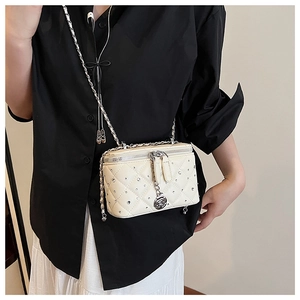 Close-up of quilted ivory vanity bag with rhinestone studs and rose charm detail
