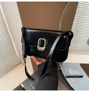 Detalle de bolso bandolera negro brillante con hebilla metálica dorada y piel sintética