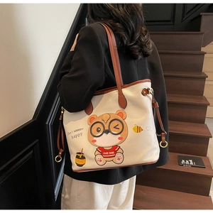 Detail view of large tote bag showing cartoon bear print and premium leather texture