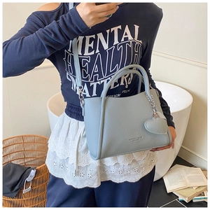 Detail view of light blue lychee pattern leather bucket bag with heart pendant charm