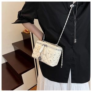 Close-up of white quilted vanity bag with crystals, silver chain, and rose pendant
