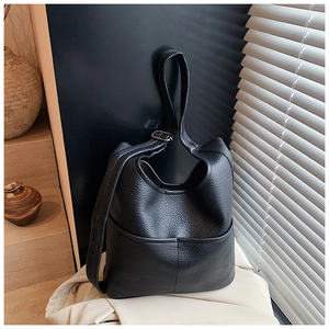 Detail einer schwarzen Beuteltasche aus Leder mit Lychee-Maserung und Metallschnalle