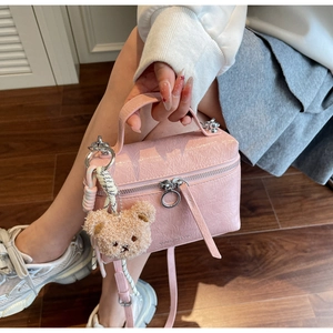 Detail of pink crocodile texture handbag featuring silver hardware and plush bear charm