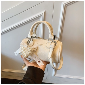 Detail of cream pleated cylinder handbag with pearl heart charm and lace bow decor