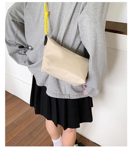 Nylon crossbody bag with yellow checkered strap shown from a top-down perspective