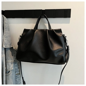 Detail of black lychee grain leather crossbody bag with pleated design and silver hardware