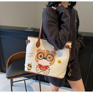 Detail of cute bear embroidery and lychee grain leather texture on white tote bag