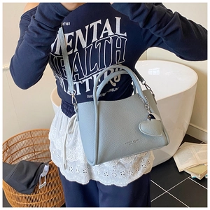 Detail of light blue lychee texture bucket bag with detachable strap and heart charm