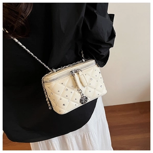 Close-up of quilted cream crossbody bag with sparkling rhinestones and rose pendant