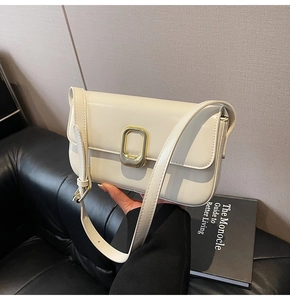 Detalle del bolso blanco crema con hebilla de metal dorado y acabado liso de alta calidad