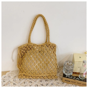 Detailed macro view of beige straw tote bag featuring wheat-knot weave and tassel detail