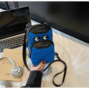 Detailed view of mini canvas crossbody phone bag with cartoon eyes and laptop backdrop