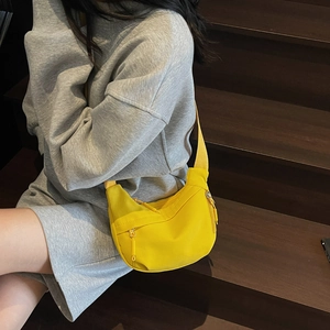 Detail of bright yellow nylon crescent bag with front zipper and matching woven strap