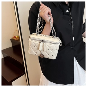Close-up of quilted vanity case bag featuring silver rivets and elegant chain strap