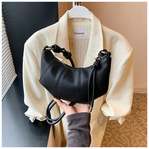 Detailaufnahme der schwarzen Croissant-Tasche mit genarbtem Leder und Knoten am Griff