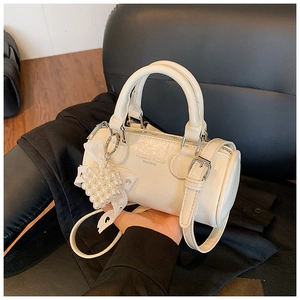 Detail of cream white barrel bag with silver hardware and pearl heart charm accessory