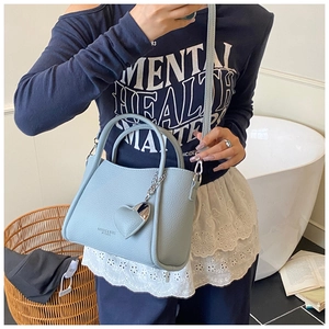 Detailed view of light blue lychee pattern leather tote bag with heart charm and strap