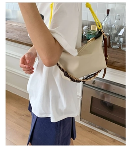 Detail of off-white fabric bag with vibrant yellow rope strap and metallic chain accents