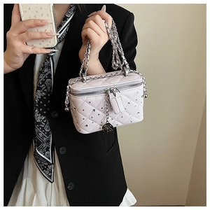 Close-up of beige quilted box bag with metal chain strap and rose zipper detail