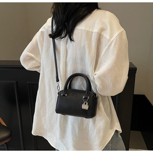 Detail of black pebbled leather mini Boston bag featuring silver hardware and a lock charm