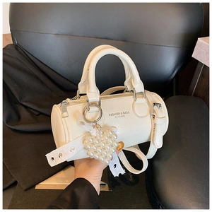 Detail of white cylindrical leather bag with pearl heart charm and lace ribbon
