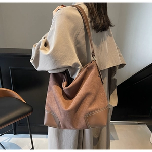 Detail of vintage brown suede hobo bag with contrast stitching and leather corner patches