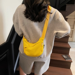 Detail of bright yellow canvas crescent crossbody bag with adjustable strap and side zipper