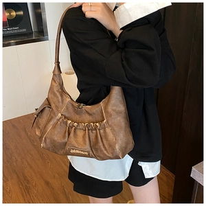Detail of vintage brown pleated hobo bag with metallic logo and textured PU leather