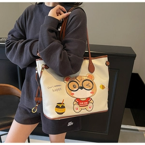 Detail of large white tote bag featuring cute cartoon bear print and brown leather straps
